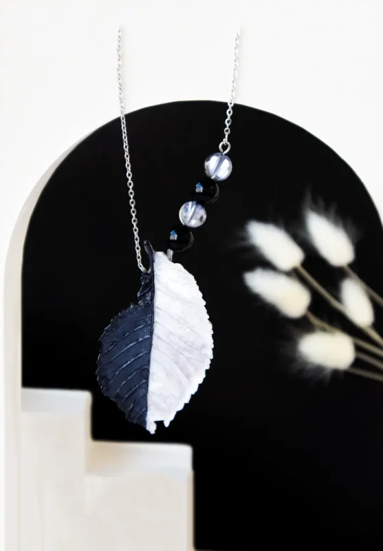 نمای نزدیک گردنبند سیاه و سفید برگ آرتونیس با سنگ آبسیدین و مون‌استون برند سانیا