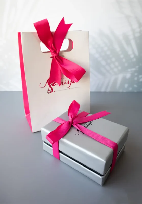 بسته‌بندی هدیه برند سانیا شامل جعبه نقره‌ای و پاکت سفید با روبان سرخابی