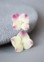 گوشواره میخی دخترانه شیک مدل ارغوان با گل طبیعی هورتانسیا سفید و ارغوانی، طراحی شده با رزین شفاف برای حفظ بافت و رنگ واقعی گل‌ها