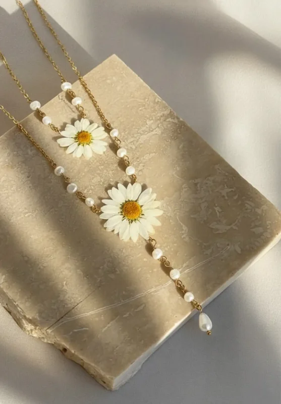 گردنبند رزینی با گل بابونه مدل نگارین، ساخته‌شده با مرواریدهای پرورشی و زنجیر طلایی روی سنگ مرمر