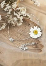 چوکر گل بابونه طبیعی هایا از برند سانیا، ساخته شده با گل بابونه واقعی کاور شده با رزین UV، بند نامرئی و قفل استیل روی زمینه چوبی.