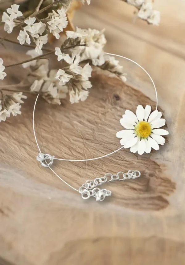 چوکر گل بابونه طبیعی هایا از برند سانیا، ساخته شده با گل بابونه واقعی کاور شده با رزین UV، بند نامرئی و قفل استیل روی زمینه چوبی.